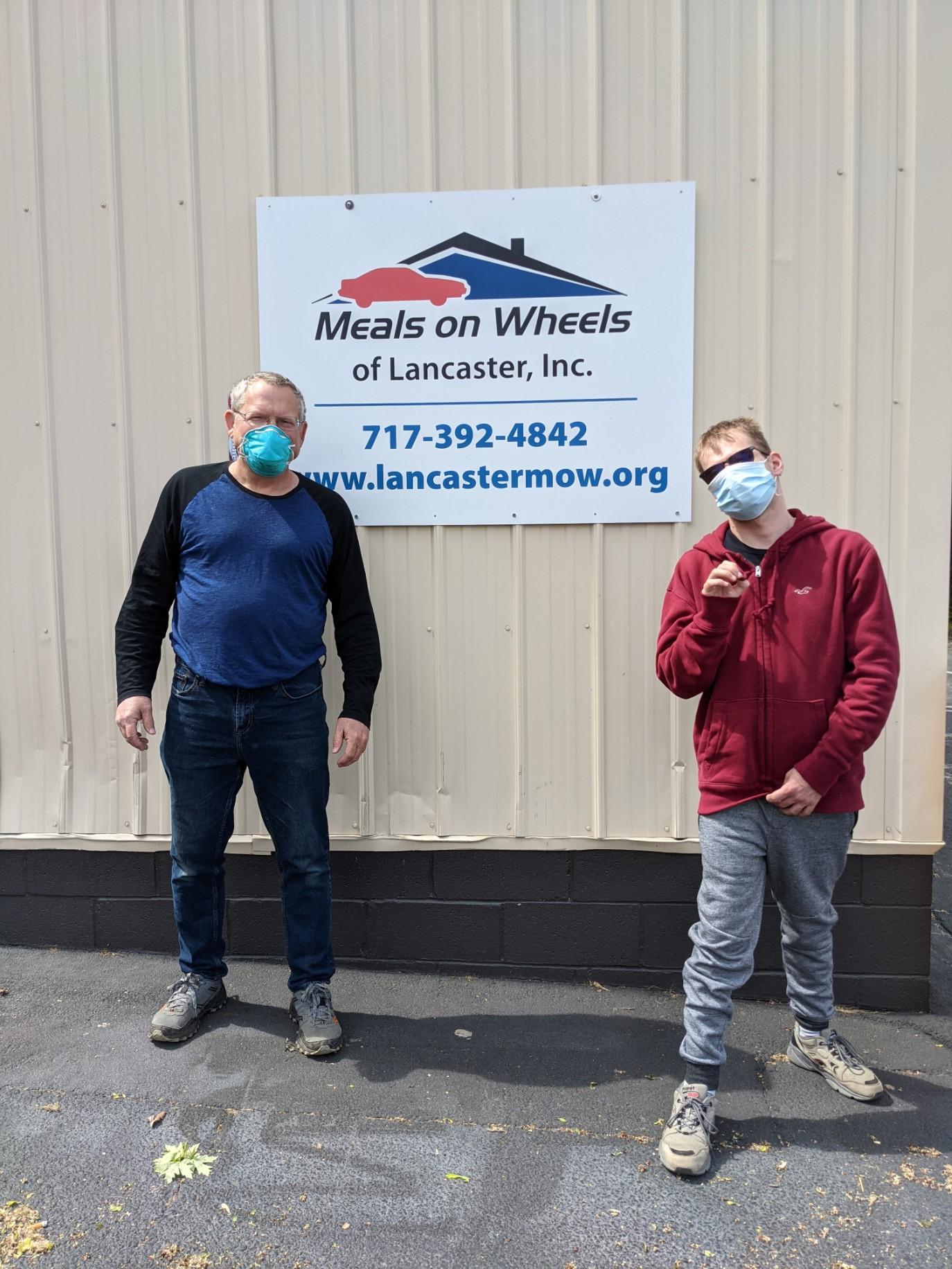 meals on wheels volunteers standing in front of a sign